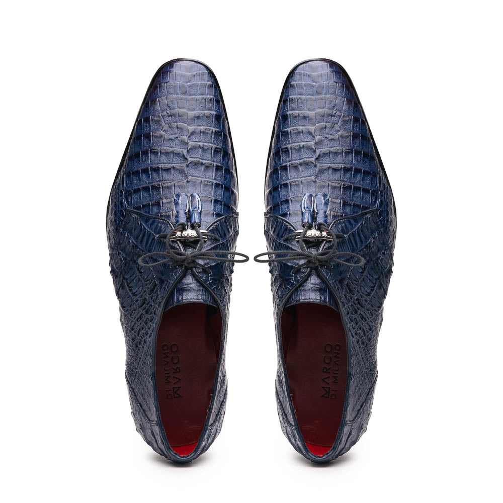 The Lacio Navy by Marco Di Milano are luxury dress derby shoes made from genuine caiman crocodile leather, featuring elegant tassels, a red interior lining, and tan leather soles stamped with the brand’s name.