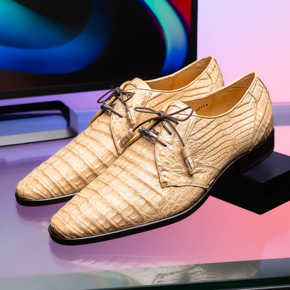A pair of beige Marco Di Milano Lacio Orix shoes in genuine caiman crocodile, featuring a luxury derby design with dark brown laces—one upright, the other on its side to display the detailed sole.