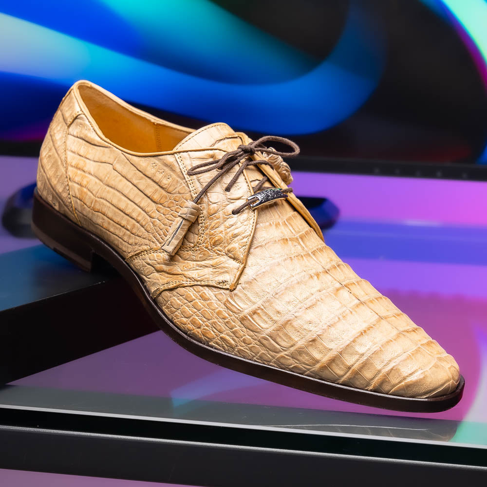 A pair of beige Marco Di Milano Lacio Orix shoes in genuine caiman crocodile, featuring a luxury derby design with dark brown laces—one upright, the other on its side to display the detailed sole.
