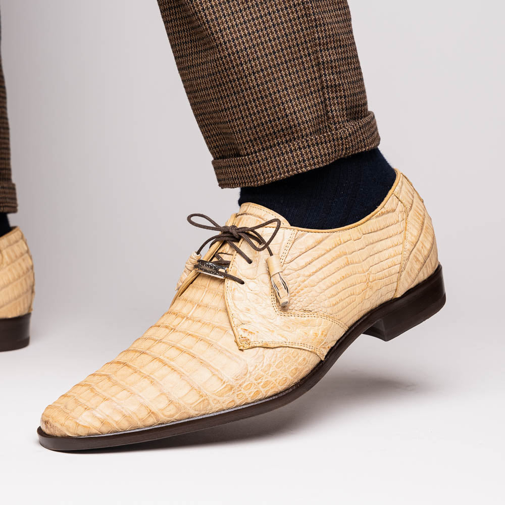 A pair of beige Marco Di Milano Lacio Orix shoes in genuine caiman crocodile, featuring a luxury derby design with dark brown laces—one upright, the other on its side to display the detailed sole.