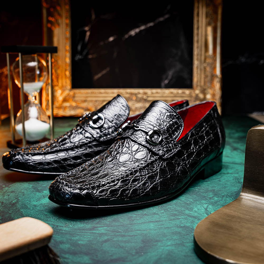 A pair of Marco Di Milano Landro Black crocodile-pattern luxury loafers with metal bit detail: one shoe stands upright, the other lies on its side displaying the tan sole labeled "Marco Di Milano.