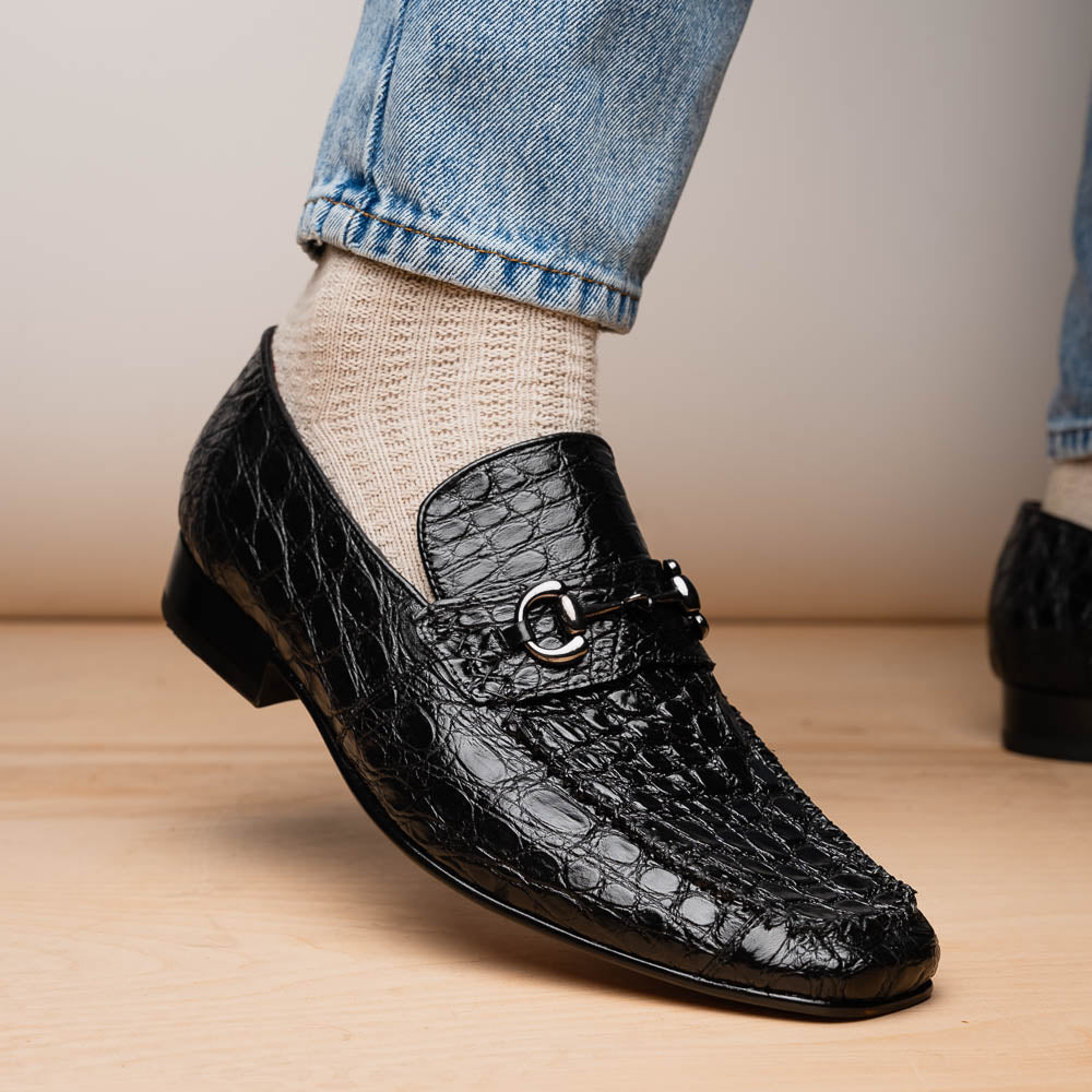 A pair of Marco Di Milano Landro Black crocodile-pattern luxury loafers with metal bit detail: one shoe stands upright, the other lies on its side displaying the tan sole labeled "Marco Di Milano.