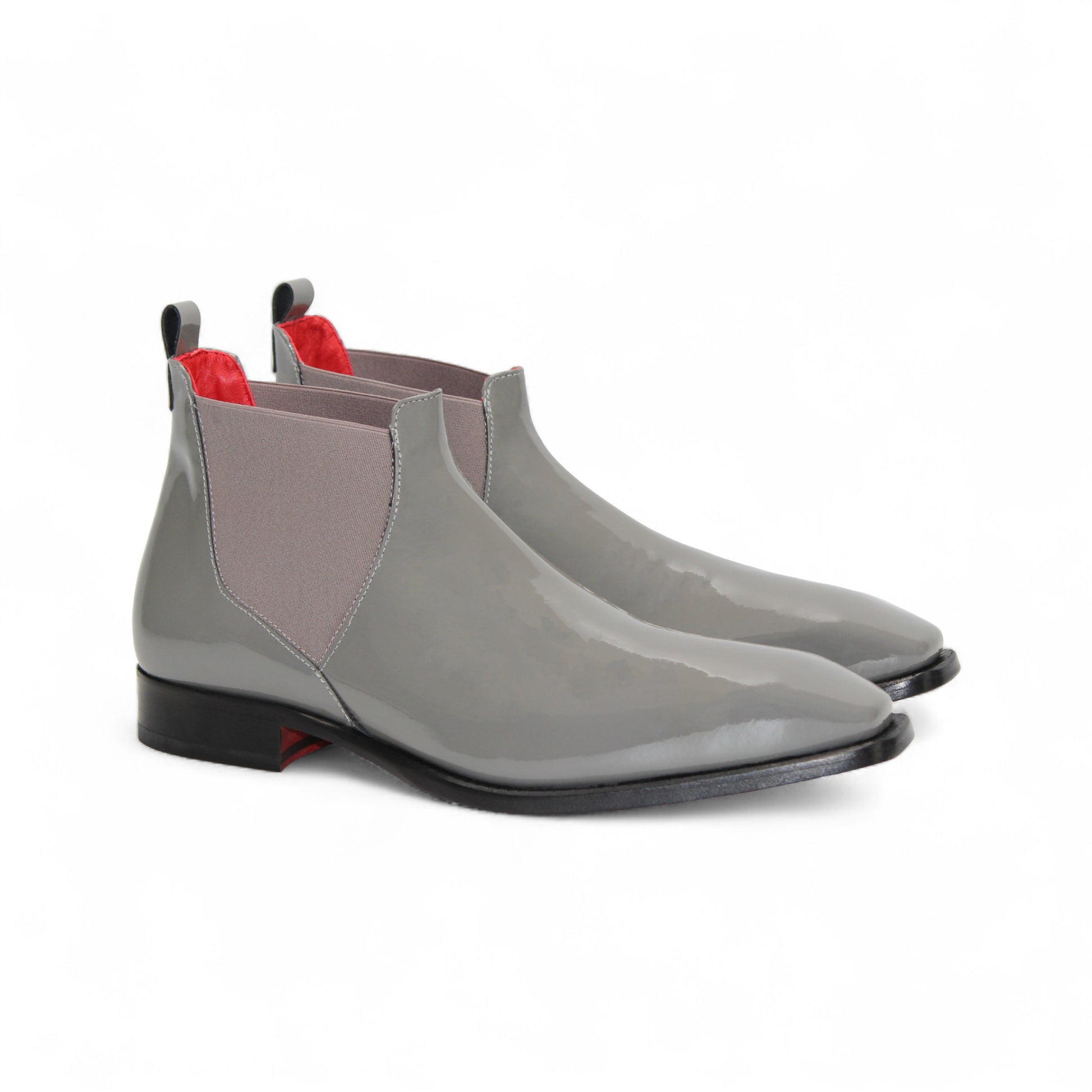 The Emilio Franco Leonardo Grey is a glossy Italian patent leather Chelsea boot with side elastic panels, low black heel, and red accents on the pull tab and lining—luxury formal footwear by Emilio Franco, shown on a white background.