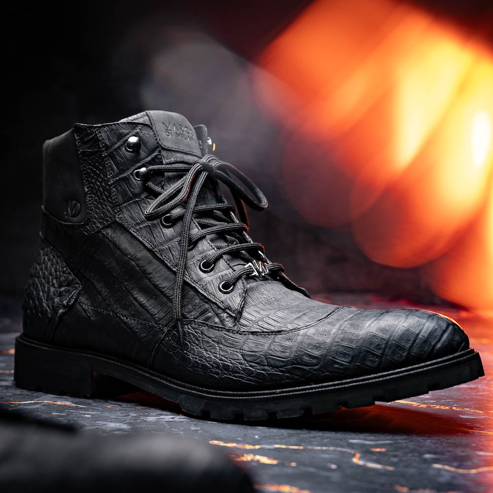 The Leoni Oil Black boots by Marco Di Milano feature genuine caiman leather in a crocodile texture, black laces, and rugged rubber soles—luxurious footwear with striking details.