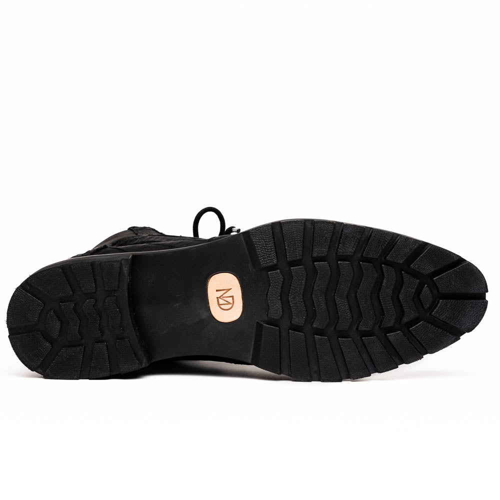 The Leoni Oil Black boots by Marco Di Milano feature genuine caiman leather in a crocodile texture, black laces, and rugged rubber soles—luxurious footwear with striking details.