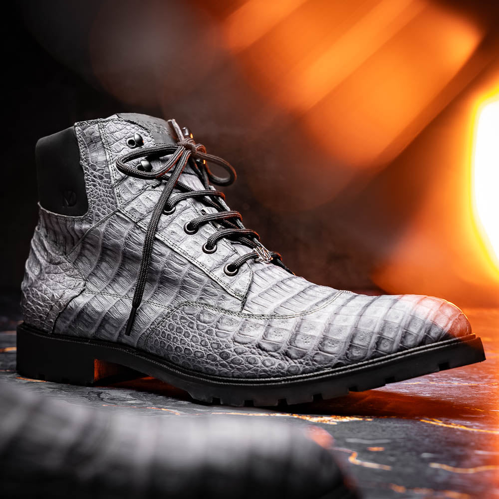 The Leoni Oil Gray boot by Marco Di Milano features a gray, crocodile-patterned design in genuine caiman leather with black laces, a thick rugged sole, and hand-painted finishes—all showcased on a white background.