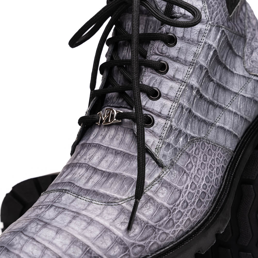 The Leoni Oil Gray boot by Marco Di Milano features a gray, crocodile-patterned design in genuine caiman leather with black laces, a thick rugged sole, and hand-painted finishes—all showcased on a white background.