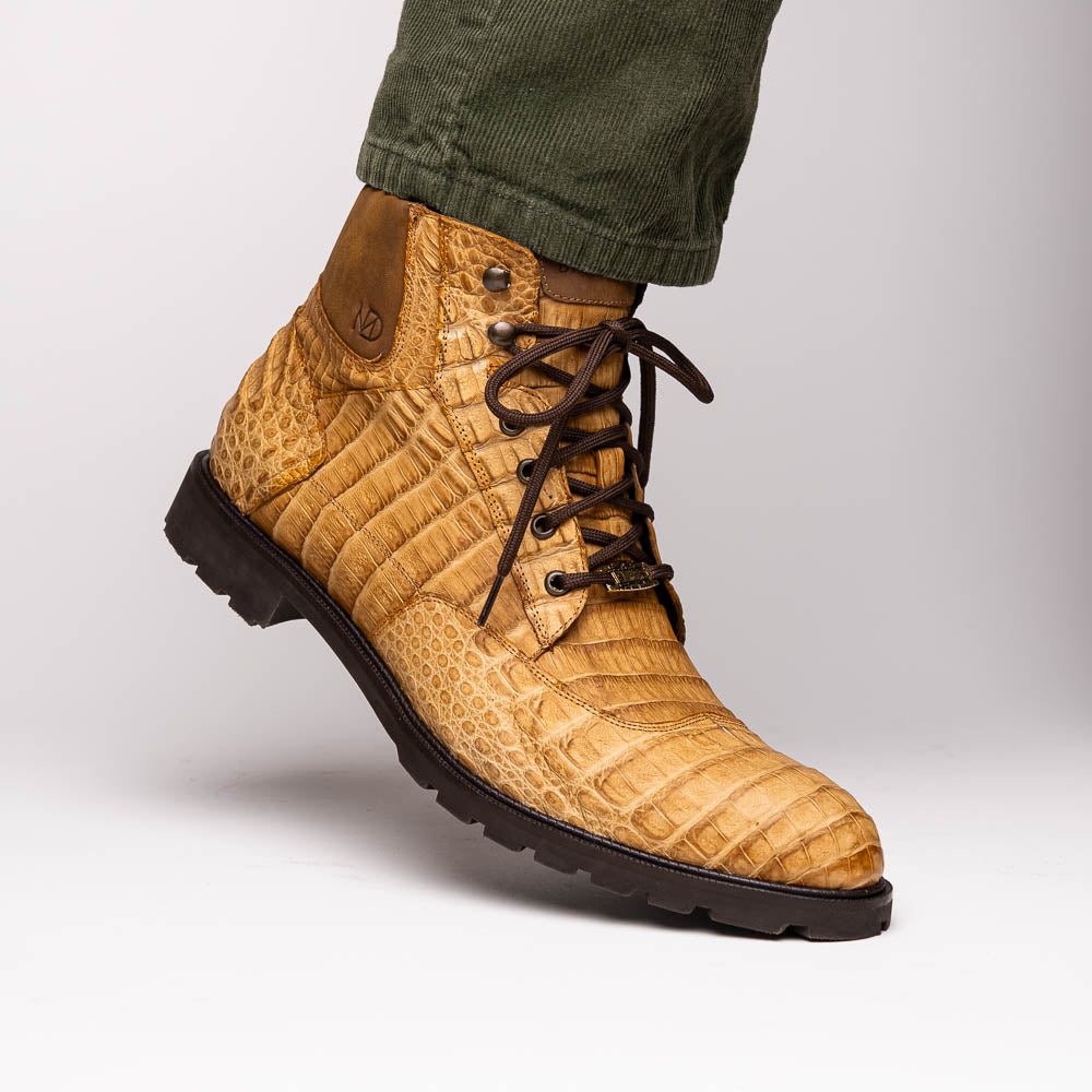 The Leoni Oil Orix by Marco Di Milano features tan crocodile-patterned leather lace-up boots with brown rubber soles, showcased upright and sideways to highlight the tread—a refined choice in luxury men's footwear.
