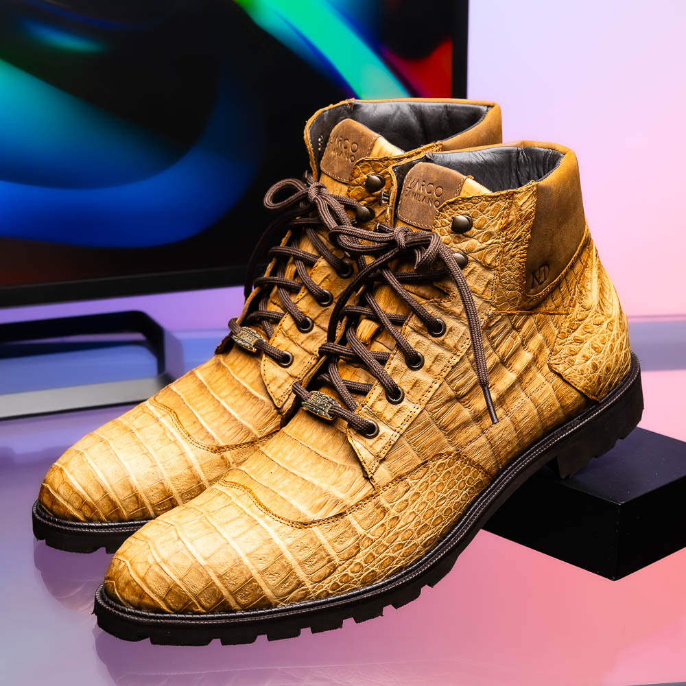 The Leoni Oil Orix by Marco Di Milano features tan crocodile-patterned leather lace-up boots with brown rubber soles, showcased upright and sideways to highlight the tread—a refined choice in luxury men's footwear.