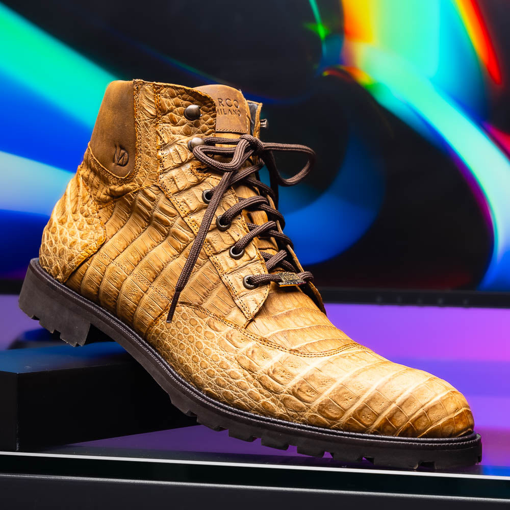 The Leoni Oil Orix by Marco Di Milano features tan crocodile-patterned leather lace-up boots with brown rubber soles, showcased upright and sideways to highlight the tread—a refined choice in luxury men's footwear.