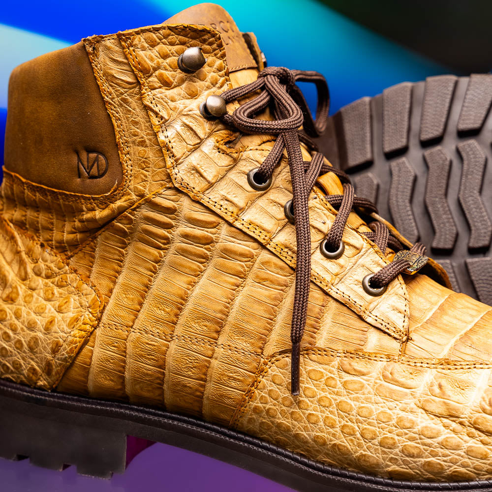 The Leoni Oil Orix by Marco Di Milano features tan crocodile-patterned leather lace-up boots with brown rubber soles, showcased upright and sideways to highlight the tread—a refined choice in luxury men's footwear.