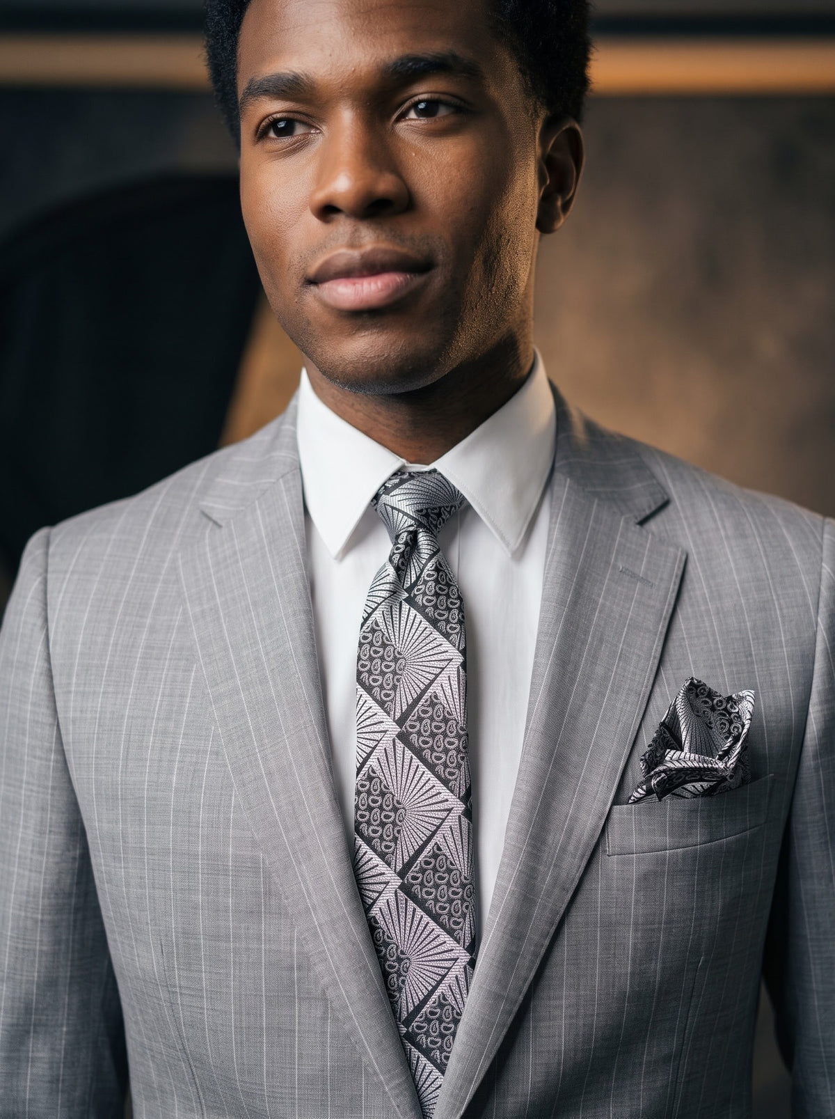 A man wearing a Tiglio Luxe Dolcetto Modern Fit Wool Suit TL26048 Grey Pinstripe, a white dress shirt, and a patterned tie with a matching pocket square.