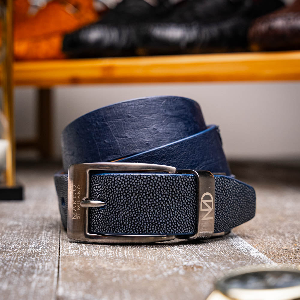The Lucca Belt Navy / Navy by Marco Di Milano is a dark blue leather belt with a silver engraved buckle, coiled on a white background—ideal for pairing with luxury footwear or matching ostrich-stingray styles.