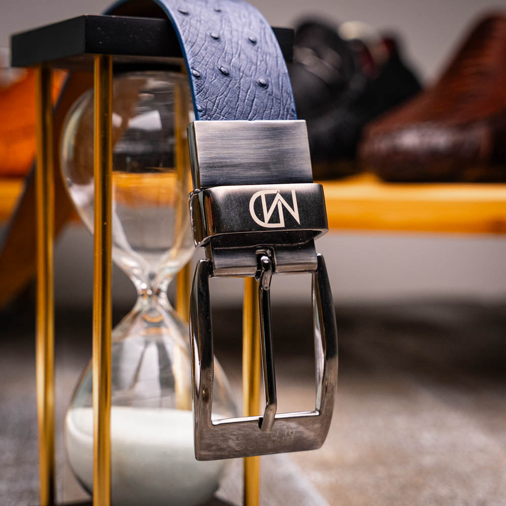 The Lucca Belt Navy / Navy by Marco Di Milano is a dark blue leather belt with a silver engraved buckle, coiled on a white background—ideal for pairing with luxury footwear or matching ostrich-stingray styles.