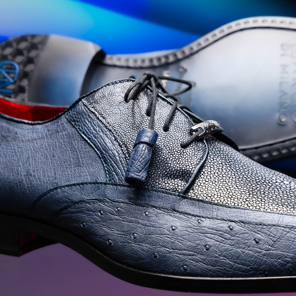 The Lucca Navy by Marco Di Milano: dark blue ostrich dress derby shoes with black soles, lace-up closures, and a textured finish. One shoe stands upright while the other lays on its side, highlighting hand-painted details.