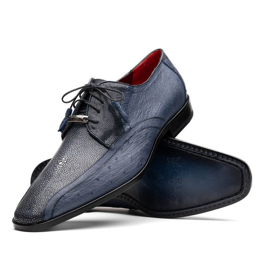 The Lucca Navy by Marco Di Milano: dark blue ostrich dress derby shoes with black soles, lace-up closures, and a textured finish. One shoe stands upright while the other lays on its side, highlighting hand-painted details.