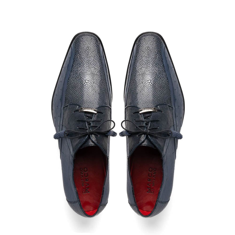 The Lucca Navy by Marco Di Milano: dark blue ostrich dress derby shoes with black soles, lace-up closures, and a textured finish. One shoe stands upright while the other lays on its side, highlighting hand-painted details.
