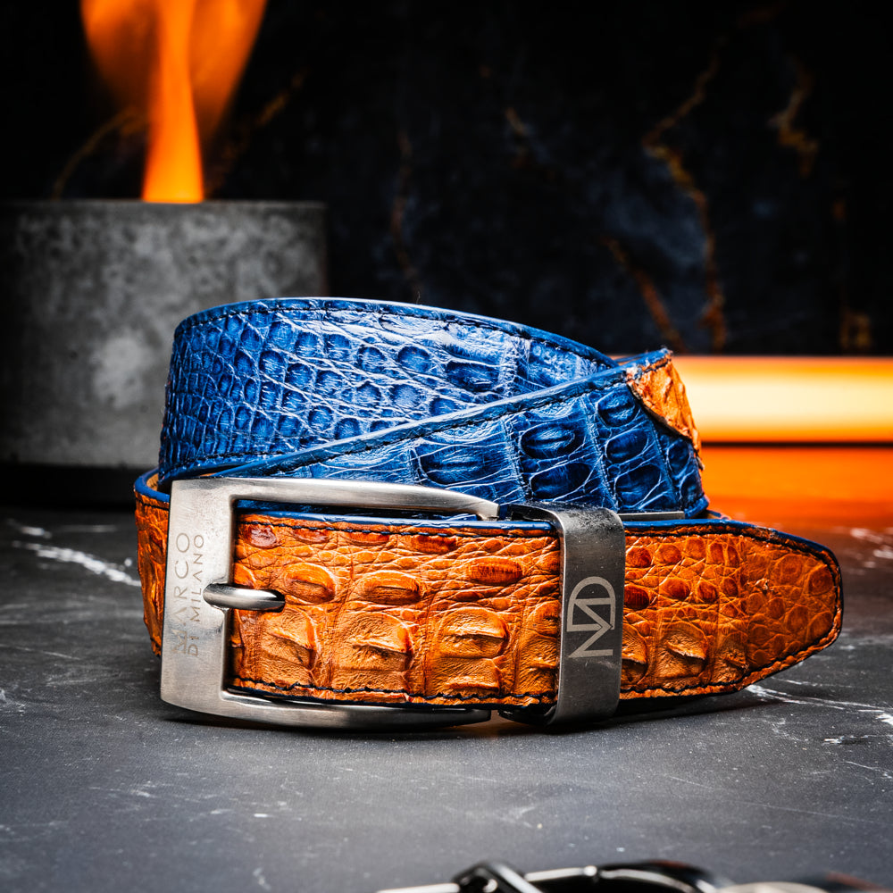 The Luciano Belt in Blue and Brandy by Marco Di Milano—both crafted from genuine caiman leather and adorned with silver buckles—are elegantly coiled together against a white background.