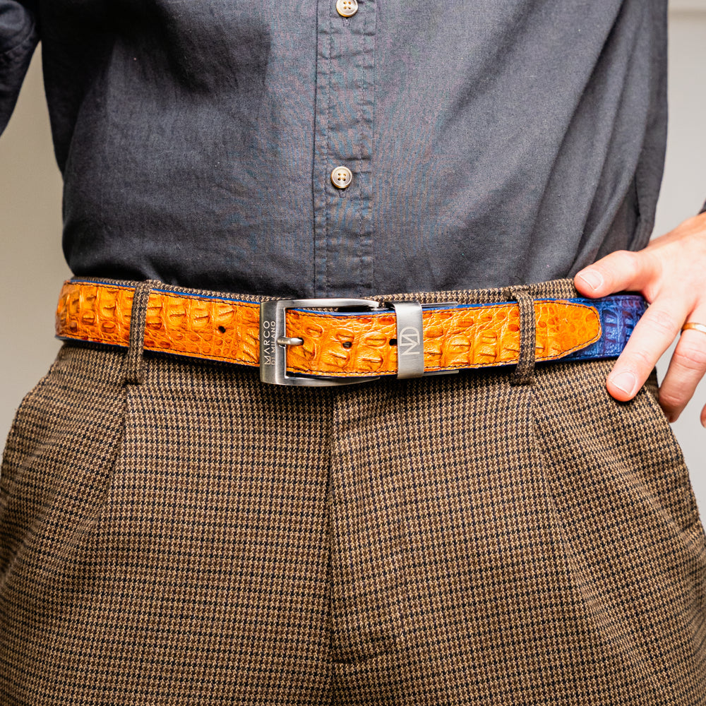 The Luciano Belt in Blue and Brandy by Marco Di Milano—both crafted from genuine caiman leather and adorned with silver buckles—are elegantly coiled together against a white background.