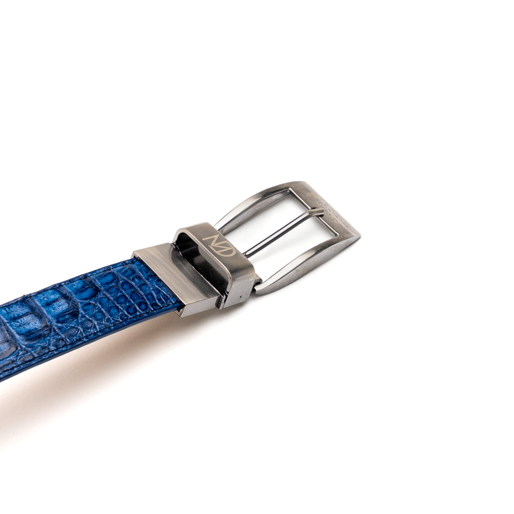 Introducing the Luciano Belt Navy / Brown by Marco Di Milano, a handcrafted luxury belt featuring an exotic crocodile-patterned leather in striking blue and dark brown sections with a refined silver buckle, elegantly coiled on a white background.