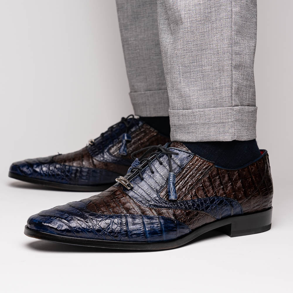 The Luciano Navy / Brown by Marco Di Milano: luxury men's wingtip derby shoes in dark blue and brown genuine caiman, shown upright and on its side to display the branded sole.