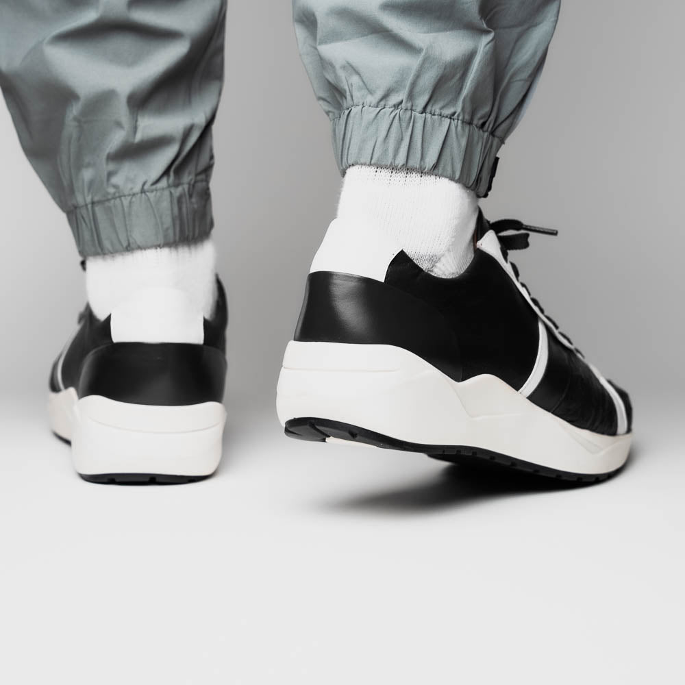The Marco Di Milano Lyon II Black / White sneakers feature textured leather uppers, black laces, and rubber soles, displayed against a plain white background.