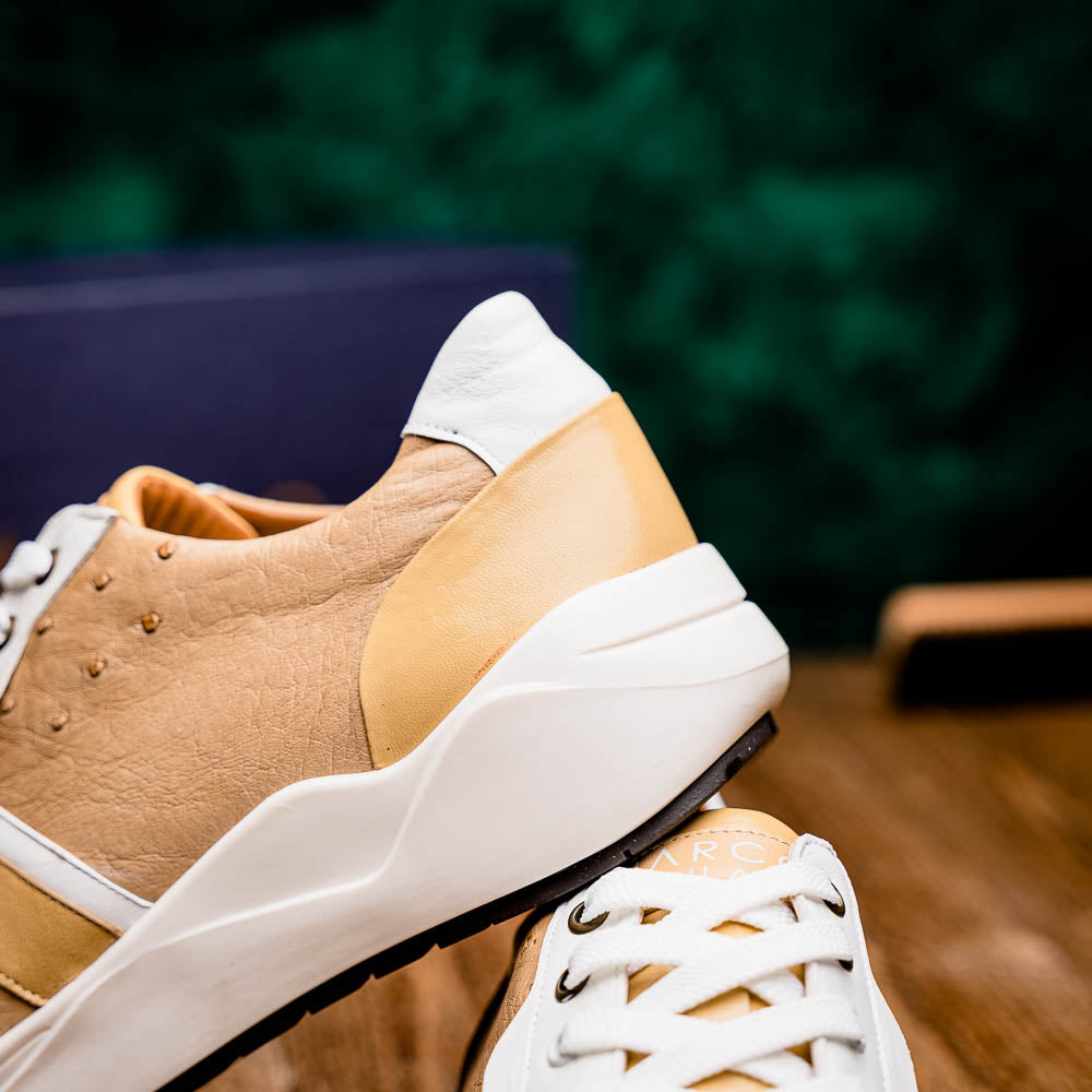 The Marco Di Milano Lyon II Orix / White sneakers feature beige and white ostrich quill-textured uppers and black rubber soles—an ideal choice for those seeking luxury footwear.