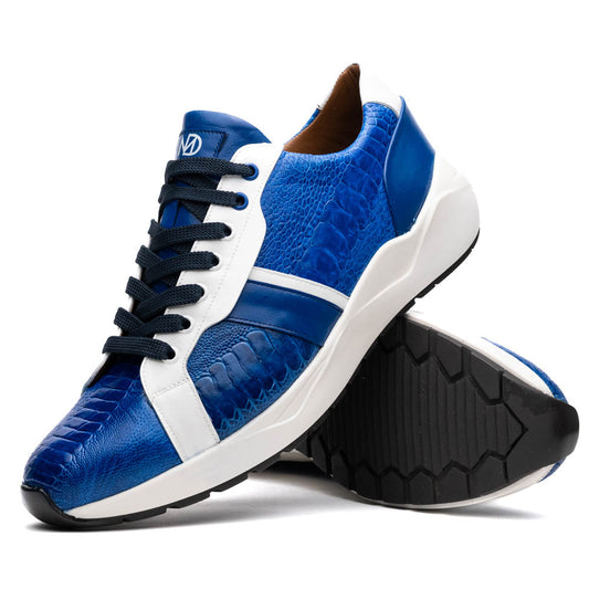The Marco Di Milano Lyon Blue / White sneakers feature blue and white tones, black laces, textured side panels, and sleek black outsoles, with one shoe displayed stylishly on its side against the other.