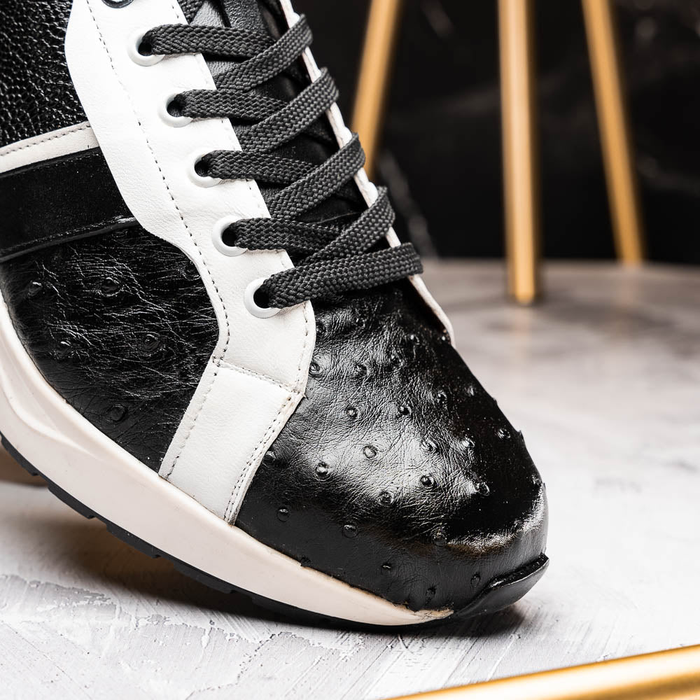 The Marco Di Milano Lyon Black / White sneakers feature a hand-painted, textured pattern, black laces, and rubber soles—one shoe shown upright, the other propped behind.