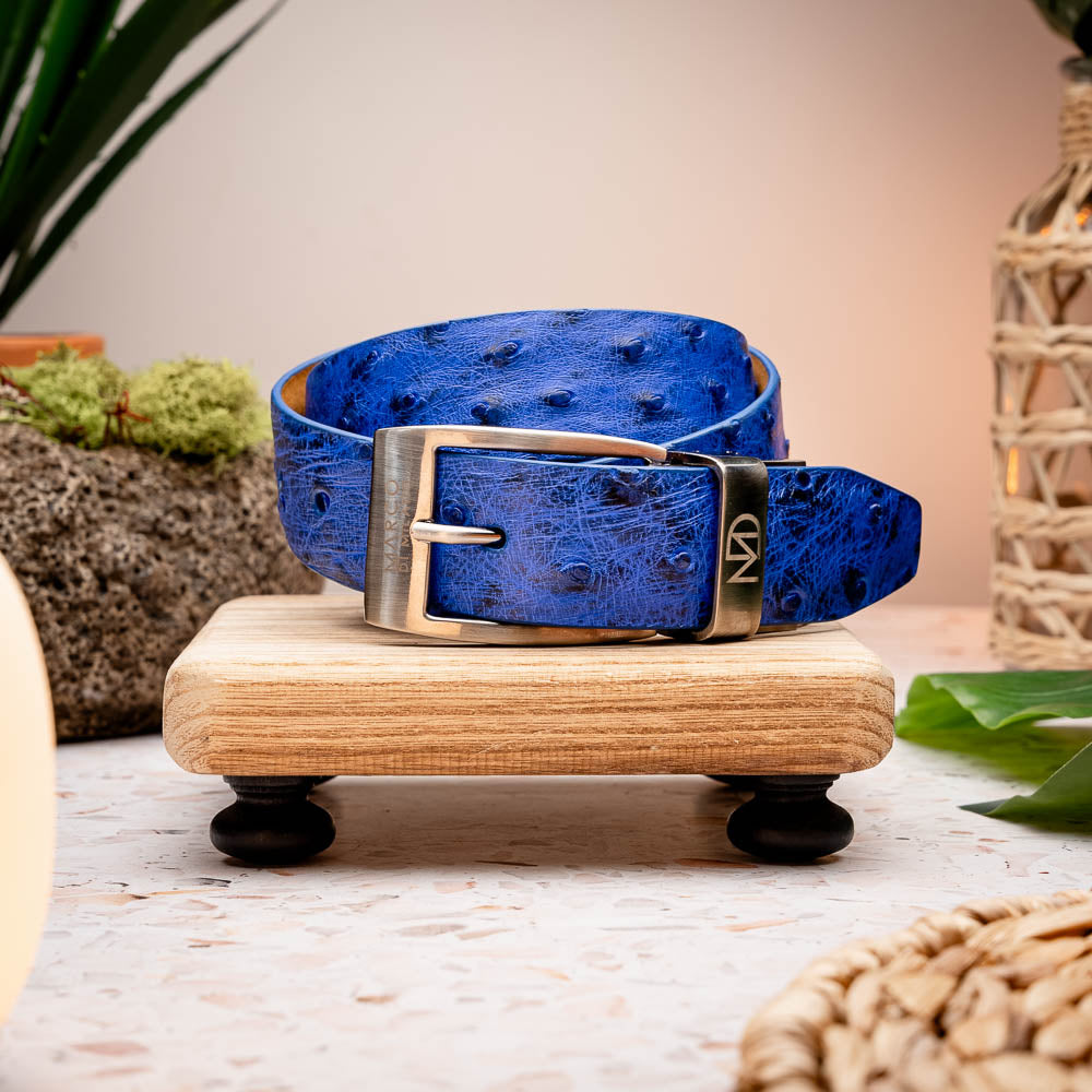 The Domenico Belt Electric Blue by Marco Di Milano features textured leather and a silver "MD" engraved buckle, pairing perfectly with luxury footwear. Experience sophistication inspired by classic ostrich belts.