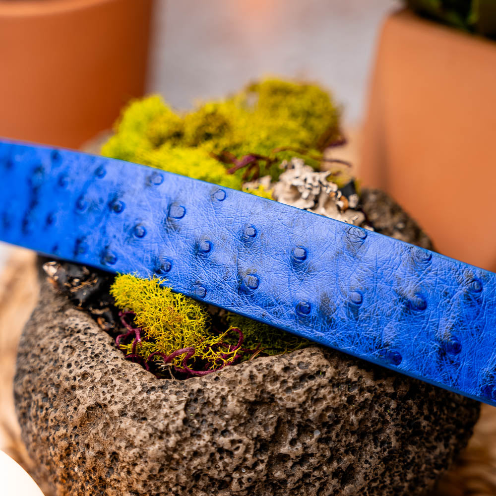 The Domenico Belt Electric Blue by Marco Di Milano features textured leather and a silver "MD" engraved buckle, pairing perfectly with luxury footwear. Experience sophistication inspired by classic ostrich belts.