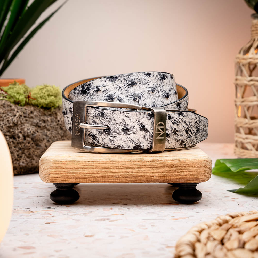The Domenico Belt Antique Newspaper by Marco Di Milano features white and black textured leather, a silver engraved buckle, and a visible "MD" logo—reflecting the brand’s signature luxury craftsmanship.