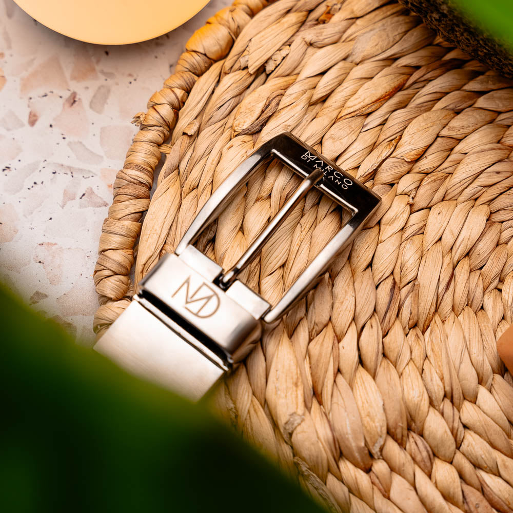 The Riccardo Belt Rustic Olive by Marco Di Milano features rustic olive caiman fuscus leather with a crocodile pattern, finished with a silver buckle engraved with the brand logo and coiled neatly.