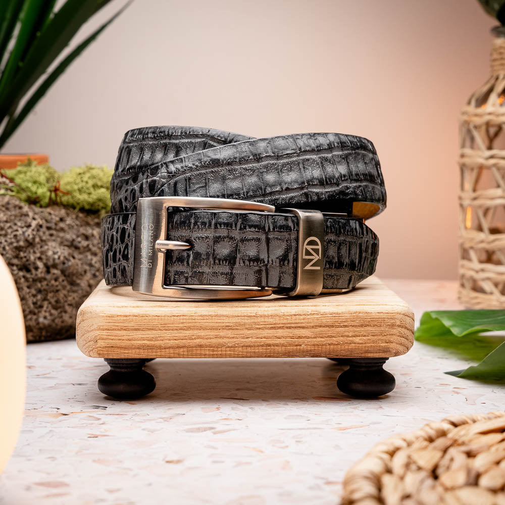 The Riccardo Belt Gray by Marco Di Milano features a genuine caiman fuscus-belly with crocodile pattern, hand-painted finish, and a silver buckle engraved with the brand’s logo—perfect for luxury footwear enthusiasts.