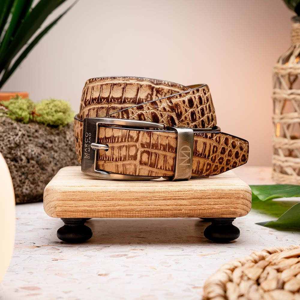 The Riccardo Belt Rustic Orix by Marco Di Milano features brown crocodile-patterned genuine caiman fuscus-belly leather and a metal buckle engraved with the brand's logo and "MD" initials.