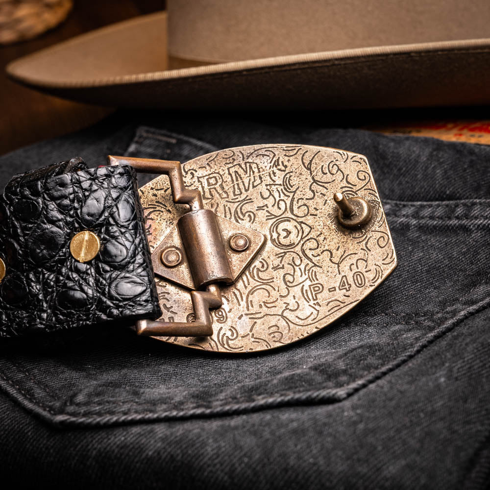 The Marlboro Belt Black by Marco Di Milano features textured hornback caiman leather and a gold buckle with stylized "MD" initials, displayed against a white background.