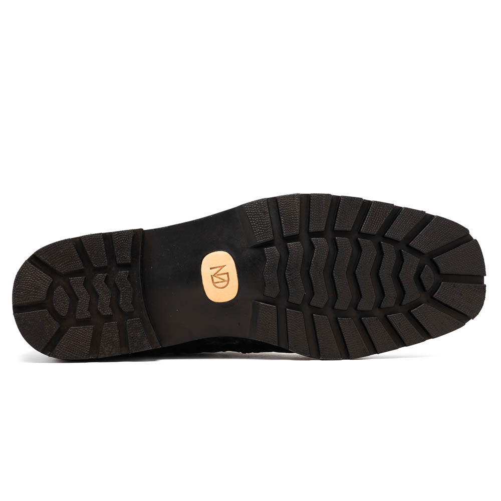 The Marco Di Milano Martinelli Black boots feature crocodile-patterned leather and thick rubber soles—one upright, one sideways to show the tread—for standout men's exotic footwear.