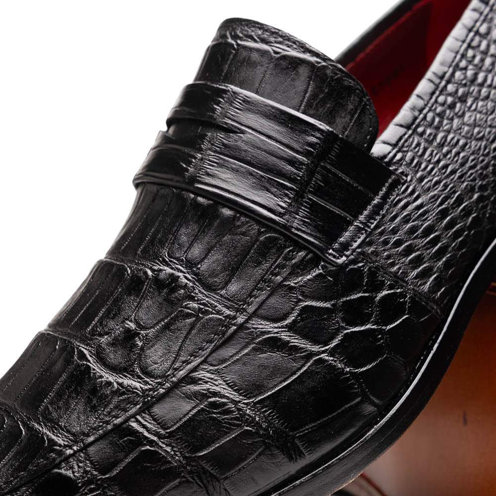 The Matteo Black by Marco Di Milano is a pair of black genuine alligator slip-on shoes with a polished brown leather sole, embossed branding, and hand-painted finishes, shown against a white background.