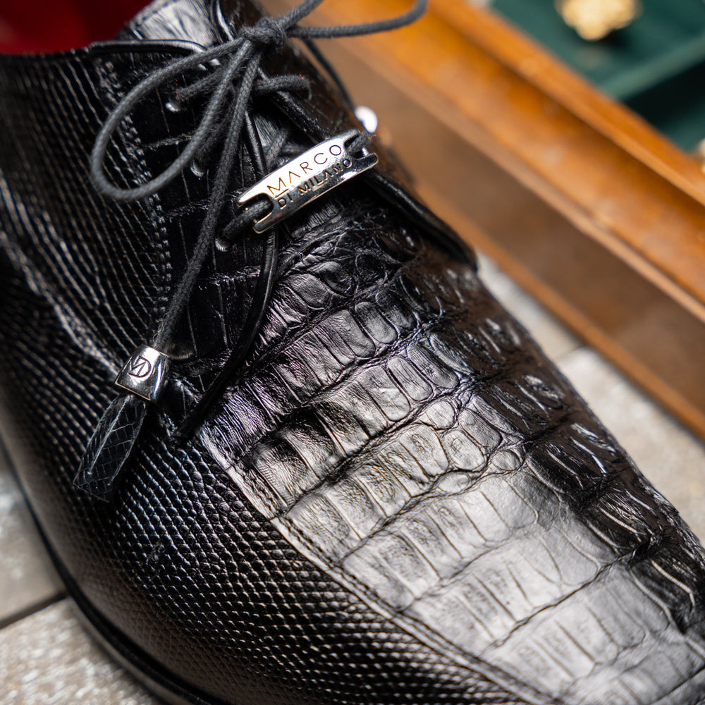 A pair of Merida Black dress derby shoes by Marco Di Milano, crafted from textured black leather caiman—one upright and one on its side revealing the brown sole stamped with the brand’s logo—an unmistakable statement in luxury footwear.