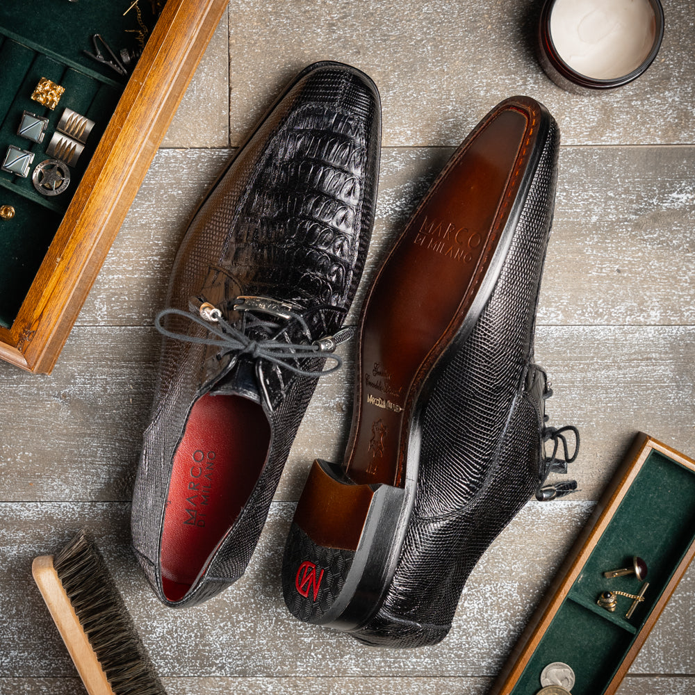 A pair of Merida Black dress derby shoes by Marco Di Milano, crafted from textured black leather caiman—one upright and one on its side revealing the brown sole stamped with the brand’s logo—an unmistakable statement in luxury footwear.
