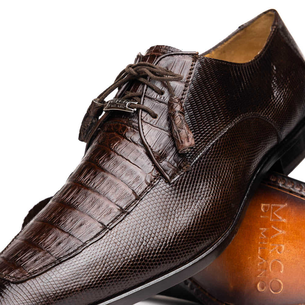 The Merida Brown by Marco Di Milano: a pair of dark brown, textured caiman dress derby shoes with laces—one upright and the other on its side revealing the sole—ideal for those seeking genuine exotic luxury footwear.