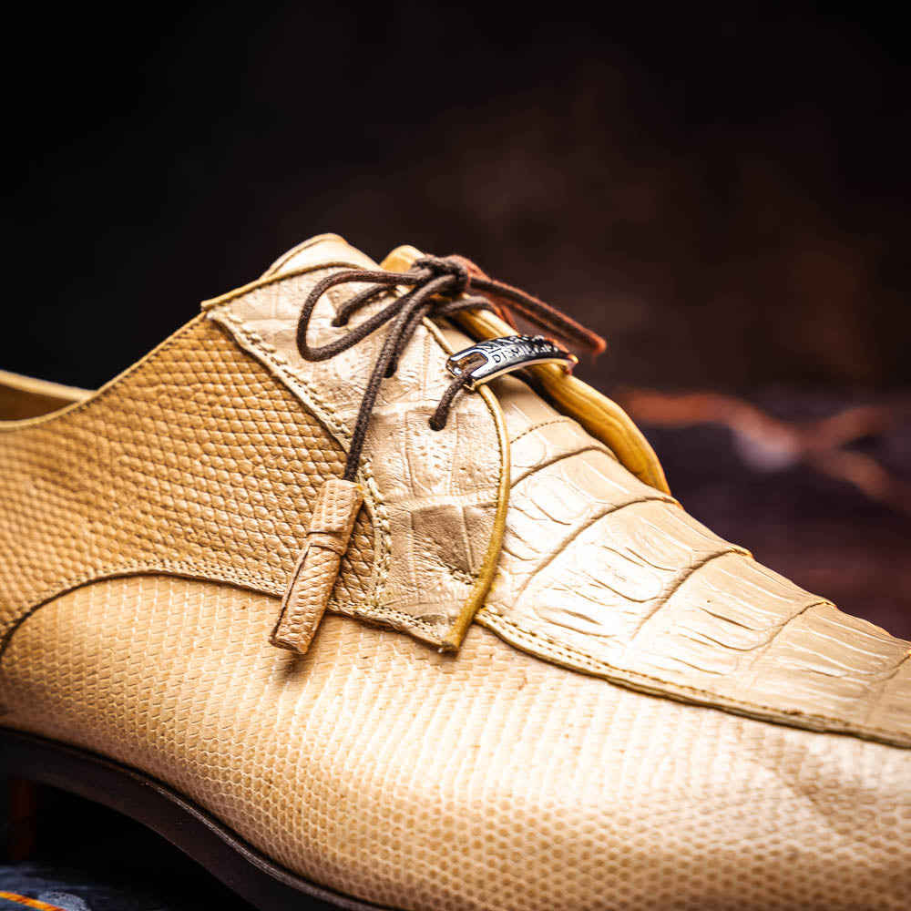 A pair of beige Merida Orix dress derby shoes by Marco Di Milano with black laces, one upright and one leaning to reveal the branded sole—a striking statement in luxury footwear.