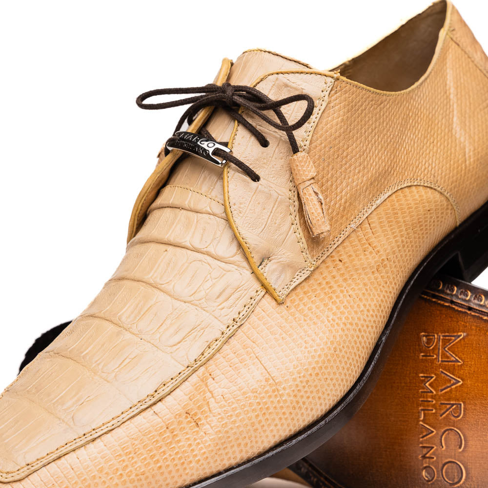 A pair of beige Merida Orix dress derby shoes by Marco Di Milano with black laces, one upright and one leaning to reveal the branded sole—a striking statement in luxury footwear.