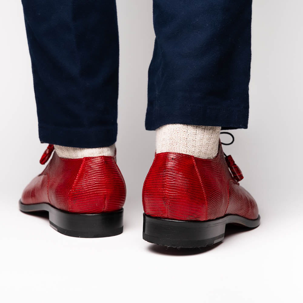 The Merida Red by Marco Di Milano are red textured leather luxury dress shoes with black laces and red tassels, shown both upright and sideways to highlight their hand-painted sole finishes.