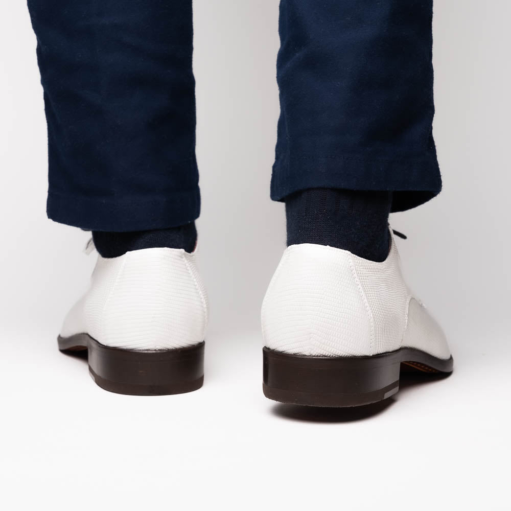 The Merida White by Marco Di Milano: luxury white textured leather caiman derby shoes with black soles, black laces, and brown leather outsoles, displayed with one shoe on its side.