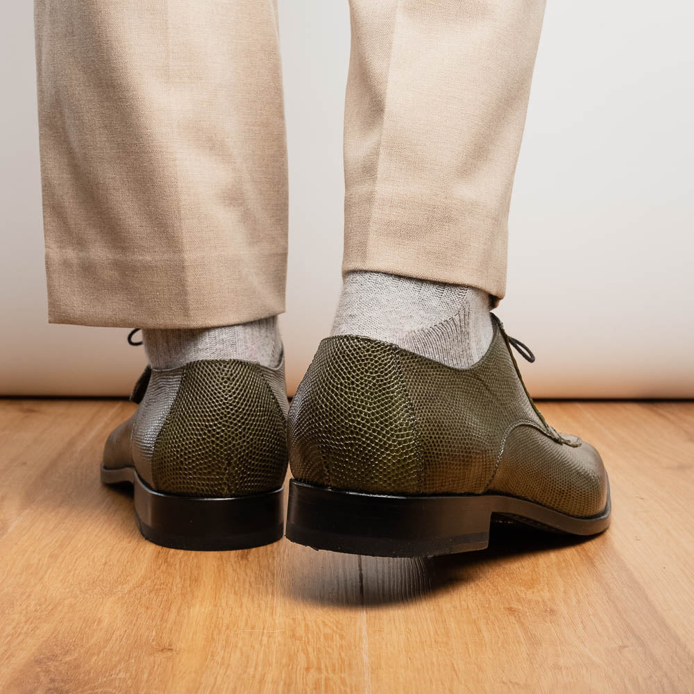 The Merida Olive Green by Marco Di Milano is a pair of olive green textured leather caiman Derby shoes with black laces, red interior lining, dark soles, embossed branding, and hand-painted finishes—a true luxury statement.