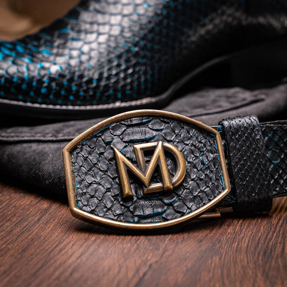 The Missouri Black / Blue boots by Marco Di Milano are handcrafted men's cowboy boots in black and blue, featuring genuine python skin and a textured snakeskin pattern—one boot upright, the other revealing the branded sole.