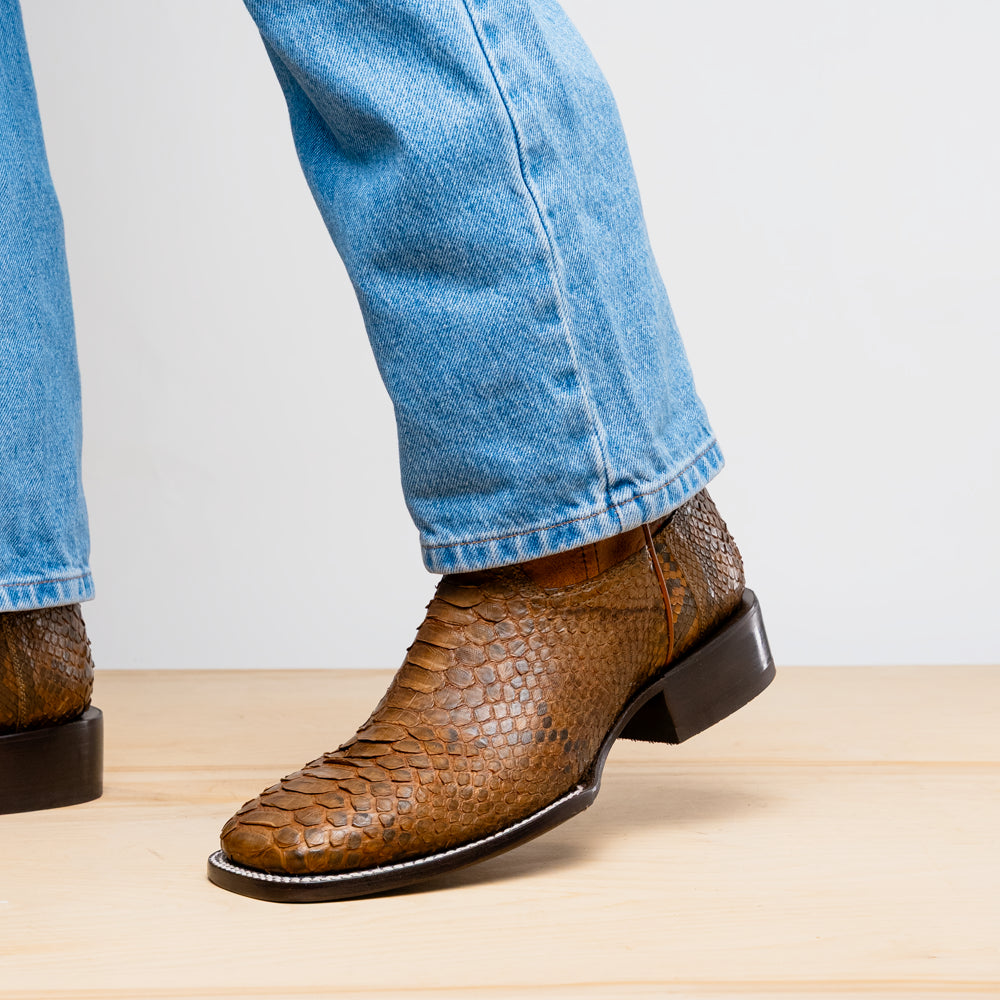 The Missouri Cognac boots by Marco Di Milano showcase classic style and premium detail with brown handcrafted leather, a textured snakeskin pattern, and distinctive branding on the sole.