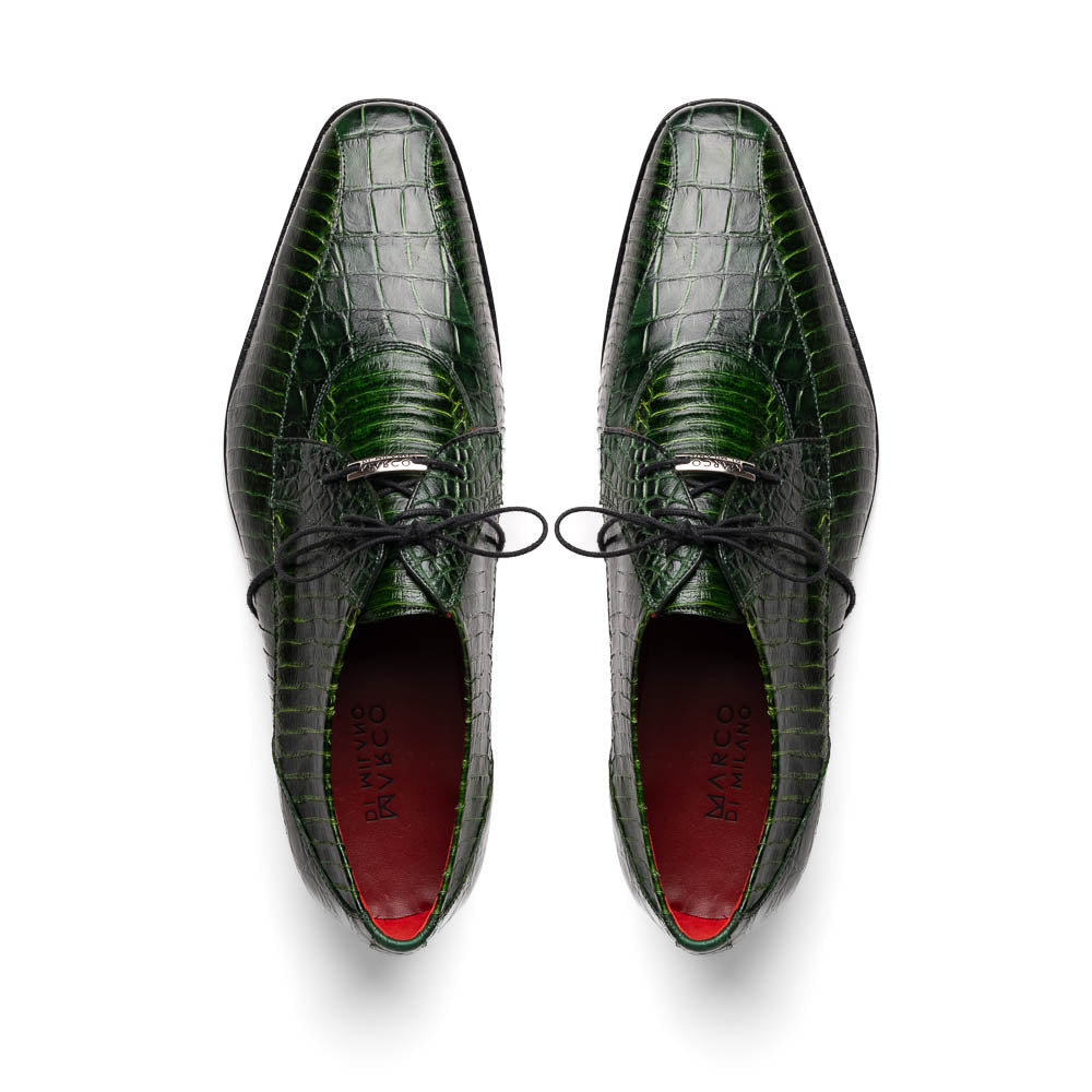 A pair of Moncalieri Green luxury shoes by Marco Di Milano, one upright with tied laces and the other on its side showing the sole—crocodile-patterned elegance at its finest.
