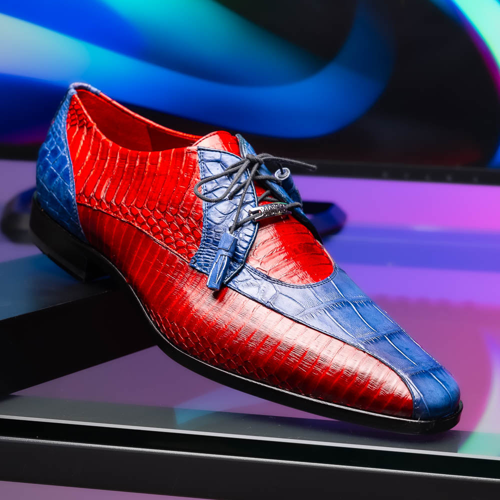 The Moncalieri Navy / Red by Marco Di Milano is a pair of men’s luxury shoes crafted from shiny red and blue crocodile leather with pointed toes, lace-up fronts, hand-painted finishes, and black soles.